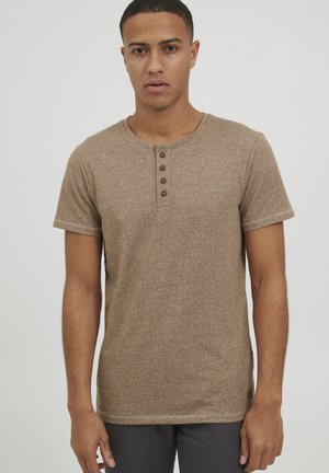 Camisa henley de manga corta marrón con un tejido texturizado, que presenta un escote redondeado y cuatro botones marrones en el frente.
