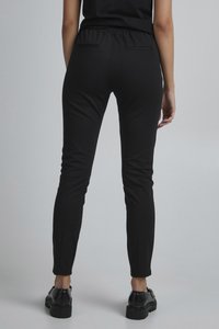 Svarta, slim-fitbyxor med elastisk midja, som har två bakfickor och en avsmalnande design. Strukturerad textil med en slät ytfinish.