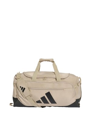 Beige ja musta urheilukassi, jossa on kaksinkertaiset kantokahvat, säädettävä olkahihna, etutasku vetoketjulla ja näyttävä musta Adidas-logo.