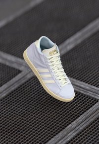 Ljusblå hög sneaker i slät läder med en mjuk inredning, tonmatchande snören och tre vita sidostripor. Mjuk beige sula.