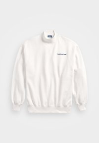 Valkoinen pitkähihainen korkeakauluksinen collegepaita, jossa on ribbireunat hihoissa ja helmassa, ja vasemmassa rinnassa pieni tummansininen Polo Ralph Lauren -logo.