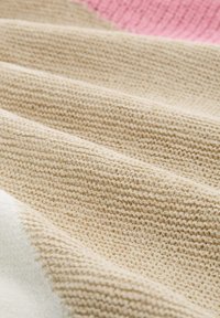 Bežinė megzto audinio medžiaga, kuri turi tekstūrinius eilių raštus ir spalvų blokavimą su šviesiai raudona ir off-white (nevisiškai balta) sekcijomis. Minkšta ir kvėpuojanti medžiaga.
