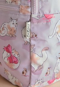 Musterstoff zeigt verschiedene verspielte Katzen und eine kleine Maus mit einer rosa Schleife, akzentuiert durch ein Cath Kidston-Label.