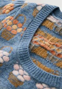 Vêtement tricoté bleu avec col côtelé présentant des motifs de paniers orange et rose tissés dans le tissu.