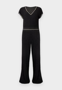 Svart jumpsuit med vertikale striper og V-hals. Har korte ermer, en tettsittende midje og utsvingte bukser. Strikket teksturert stoff.