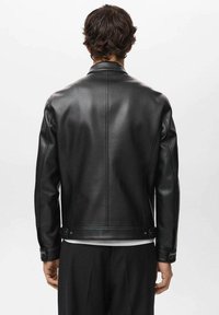 Black leather jacket with a fitted design, featuring a pointed collar, subtle stitching details, and button accents at the cuffs and hem.
