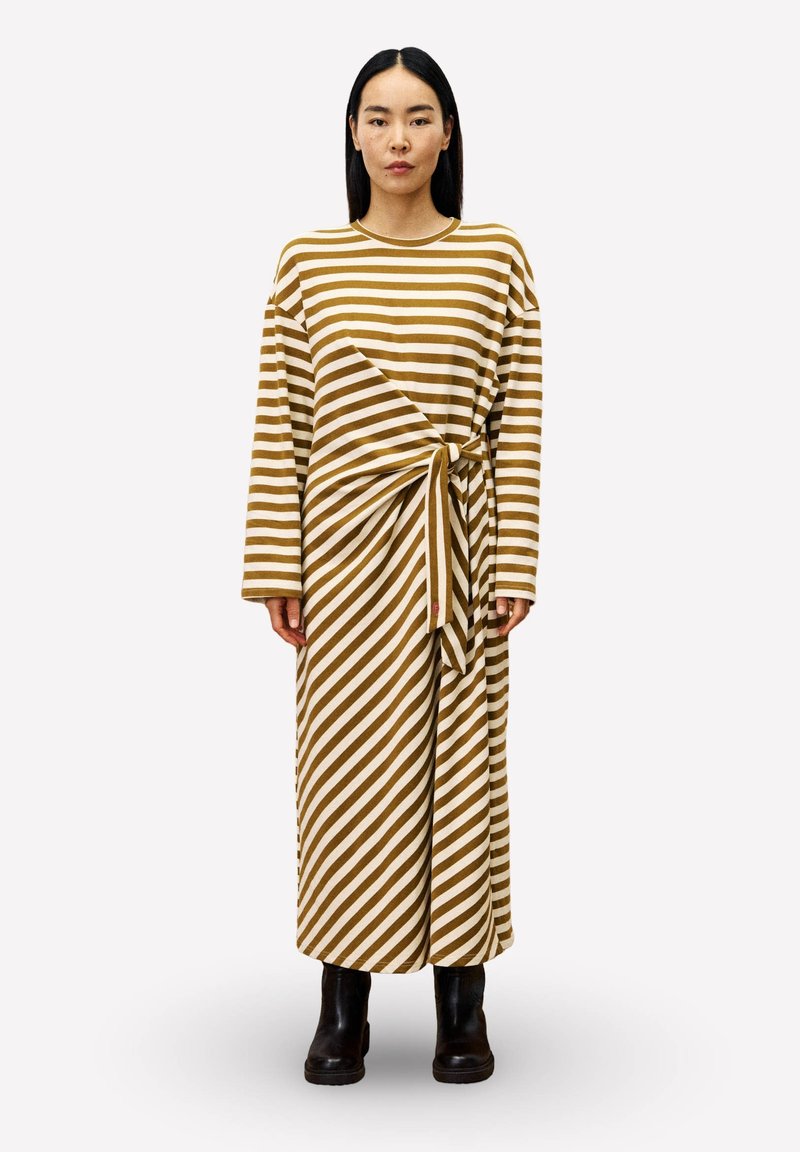 Gestreepte langarm jurk in bruin en crème, met een gedraaide knoopdetail in de taille. Draag het met zwarte enkellaarsjes.