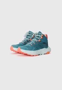 Turquoise wandelschoenen met een gestructureerde mesh-bovenkant, oranje accenten, reflecterende veters en een robuuste zool met een prominent profiel.