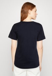 Tricou din bumbac bleu închis, cu mâneci scurte și decolteu rotund, prezentând o textură netedă și un design simplu. Vedere din spate, fără grafice.