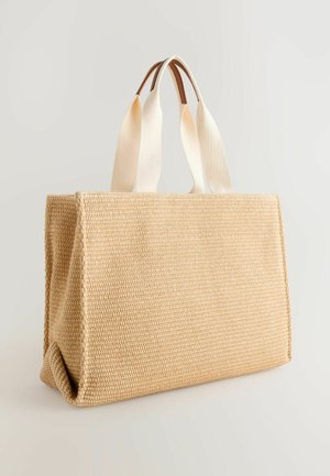 Beige gevlochten draagtas met een gestructureerd ontwerp, voorzien van twee crèmekleurige stoffen handvatten en een gladde tan accent aan de basis van de handvatten.