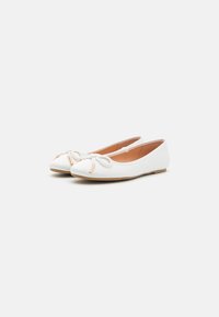 White leather ballet flats with a rounded toe, featuring a decorative bow and gold accents on the front. Flat rubber sole; smooth texture.