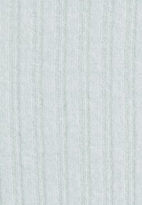 Tissu tricoté gris clair avec texture côtelée verticale et aspect doux en laine.