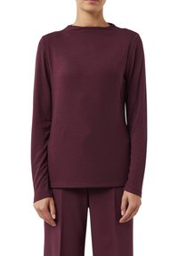 Burgunderfarbener Langarm-Oberteil aus weichem Stoff mit rundem Halsausschnitt und geradem Schnitt, zeichnet sich durch ein einfaches, klares Design aus.