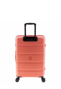 Valigia trolley rigida da cabina di colore corallo, con superficie testurizzata a linee orizzontali, manico telescopico nero e quattro ruote.