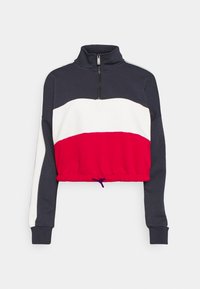 Sweat-shirt court avec col montant, présentant des blocs de couleur bleu marine, blanc et rouge, fermeture éclair, et ourlet élastique avec cordon de serrage ajustable.