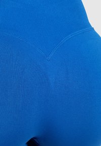 Blauwe high-waisted legging gemaakt van rekbaar materiaal met een geribbelde textuur en een gestikte V-vormige details aan de achterkant voor een betere pasvorm.