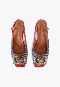 Denim slingback shoes with red patent accents, featuring a decorative gold and crystal brooch detail and a quilted tan insole.