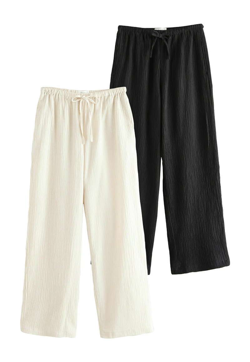 Pantaloni a gamba larga spiegazzati in crema e nero con vita elastica e dettaglio del cordoncino, che mostrano una morbida consistenza.