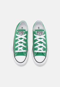 Zelené plátěné tenisky s bílými tkaničkami, černými akcenty a gumovými podrážkami. Na jazyku mají hvězdové logo. Klasický nízký design.