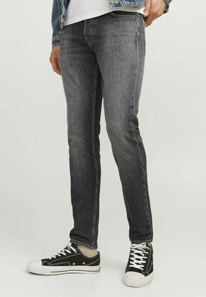 Jeans de corte slim para hombre en denim gris oscuro, con una textura suave y diseño clásico de cinco bolsillos, combinados con zapatillas negras.