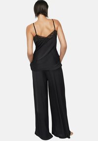 Zwarte satijnen pyjama-set met een topje met kant en verstelbare bandjes, gecombineerd met losse, rechtvallende broek.