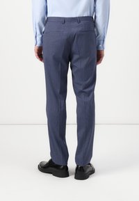 Bikses, izgatavotas no teksturēta zila auduma ar smalku pārbaudes rakstu, taisnas griezuma un divām pakaļējām kabatām. Valkātas ar melniem apaviem.