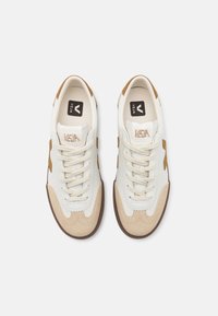 Hvite lær sneakers med brune semskede detaljer og brune gummisåler. Funksjoner inkluderer snøring og preget merkevarelogo på tungen.