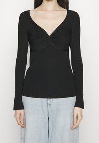 Czarna bluzka z długim rękawem, głębokim dekoltem w kształcie litery V oraz skręcanym detalem na środku. Posiada prążkowaną fakturę i lekko rozszerzane mankiety.