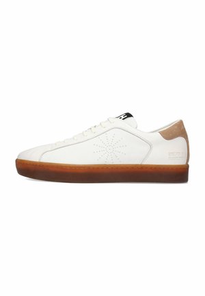 Zapatilla de cuero blanca con un diseño perforado, detalles en gamuza marrón, logo negro en la lengüeta y suela de goma marrón.