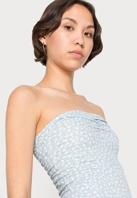 Vestido sem alças em azul-claro, com padrão floral, textura franzida e detalhes gathered na parte superior. Tecido suave e elástico.