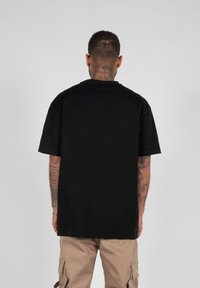Čierne bavlnené tričko s krátkymi rukávmi a okrúhlym výstrihom, s jednoduchým dizajnom a bez viditeľných vzorov alebo grafiky.