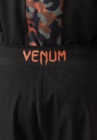 Črne športne kratke hlače z blejzarskim vzorcem na pasu; vsebujejo blagovno znamko "VENUM" v oranžni pisavi. Gladka tekstura tkanine.