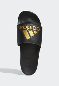 Černé skluzné sandály s širokým páskem a zlatým logem Adidas a třemi diagonálními pruhy. Texturovaná stélka pro lepší přilnavost.