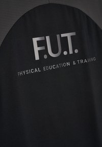 Sort stof med stort reflekterende tekst "F.U.T." over mindre tekst, der lyder "Fysisk Uddannelse og Træning."