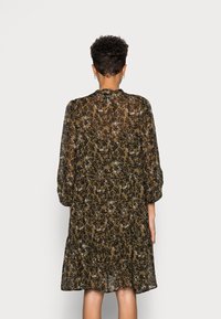 Blommig klänning i genomskinlig olivfärgad tyg, med en lös passform, långa ärmar och en flerlagers kjoldesign med mörka och ljusa blommönster.