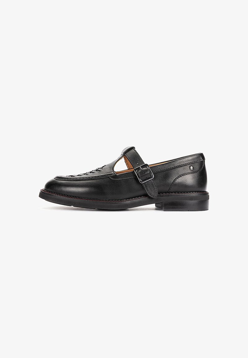 Mocassin en cuir noir avec bride latérale à boucle, petit talon et détails cousus le long de la tige et de la semelle.