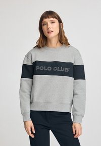 Felpa grigia con una banda orizzontale nera che presenta la scritta "POLO CLUB" in bianco. Tessuto morbido, scollo rotondo e vestibilità comoda.