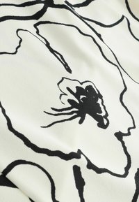 Tissu blanc avec de grandes silhouettes florales abstraites noires et des détails de pétales centraux dans un design minimaliste.