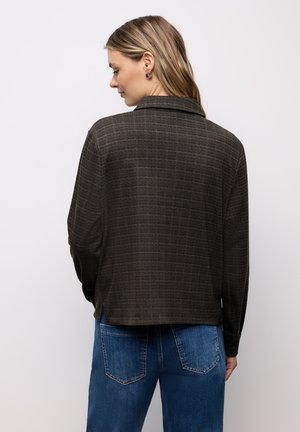 Brązowa kraciaste koszula na guziki z kołnierzykiem i długimi rękawami, wykonana z teksturowanej tkaniny, zestawiona z niebieskimi dżinsami.