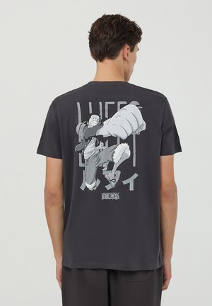 T-shirt in cotone nero con stampa grafica di un personaggio con un grande pugno e testo sul retro; collo rotondo, maniche corte.