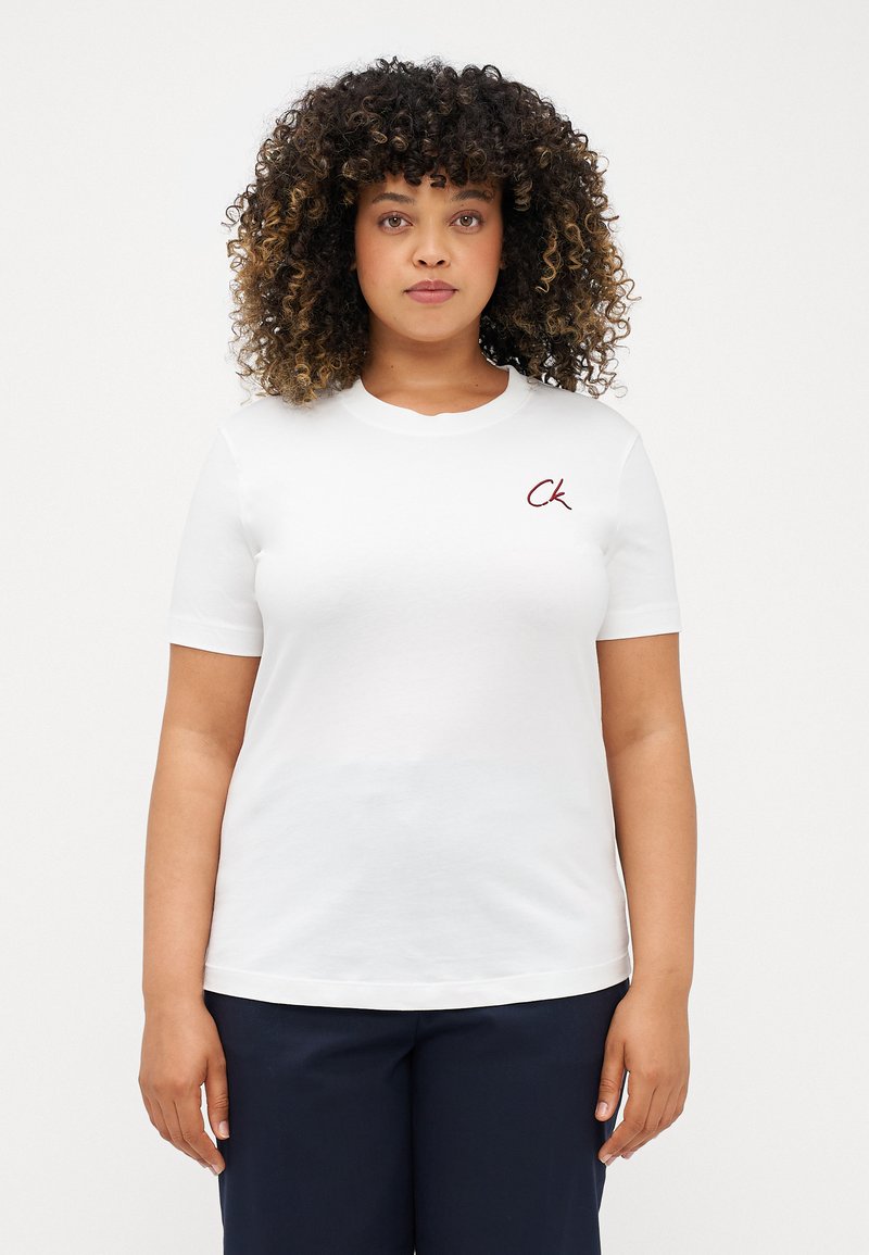 Λευκό βαμβακερό T-shirt με κοντά μανίκια, στρογγυλή λαιμόκοψη και μικρό λογότυπο "CK" σε μπορντό στο αριστερό στήθος. Απλός σχεδιασμός, λεία υφή.