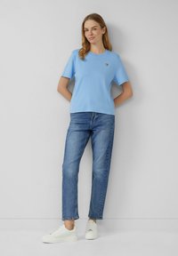 Lichtblauw katoenen T-shirt met korte mouwen en een ronde hals, gecombineerd met jeans in een middelmatige was en witte sneakers.