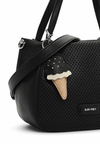 Sac à main en cuir noir texturé avec devant perforé, quincaillerie argentée et porte-clés en forme de cornet de glace attaché à la sangle.