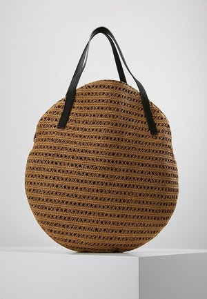 Pyöreä olkilaukku, jossa kudottu pinta, luonnollinen beige väri ja mustat nahkahihnat kontrastia ja kestävyyttä varten.