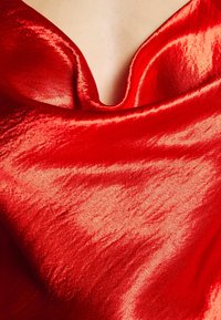 Tela de satén roja con un diseño de cuello drapeado, que presenta una textura lisa y brillante, con pliegues sutiles que crean una apariencia fluida.