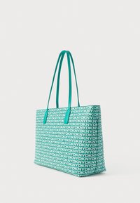 Türkizkék nagy táska ismétlődő DKNY logómintával, masszív anyagból, két hosszúkás fogantyúval a kényelmes hordozásért. Téglalap alakú.