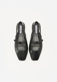 Pantofi din piele neagră, tip slingback, cu vârf pătrat, detalii texturate și o curea subțire la gleznă cu cataramă. Interior căptușit.