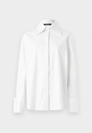 Camisa branca de algodão com colarinho pontiagudo, mangas longas e punhos abotoados. Textura suave, corte ajustado e design minimalista.