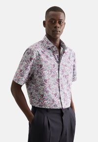 Camicia a maniche corte con colletto caratterizzata da un vivace motivo floreale in viola e blu su uno sfondo chiaro, realizzata in tessuto leggero.