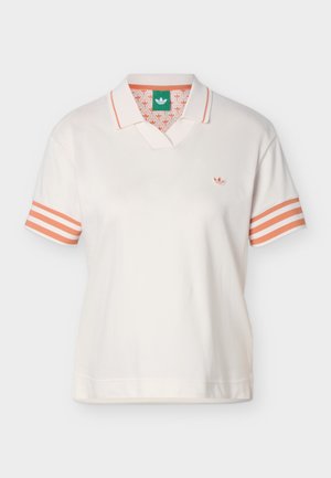 Hvit kortermet polotrøye med korallstriper på ermene og kragen, liten korallfarget logo på brystet, og mønstret innerkrage.